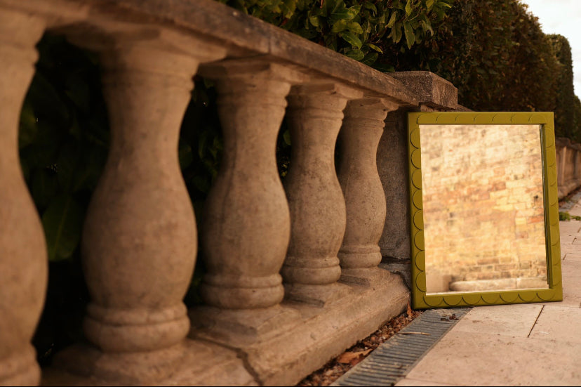 Scallop Mirror leaning against a stone wall