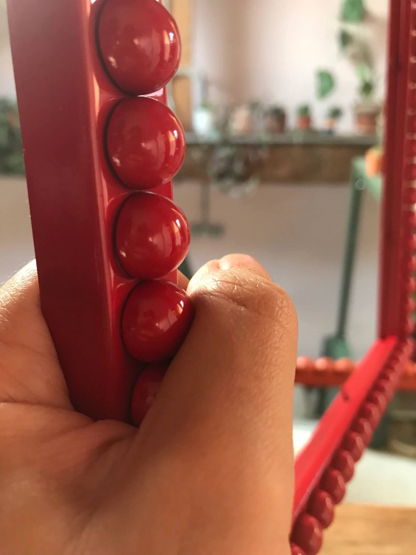 Hand holding Crimson Red Bobbin Frame
