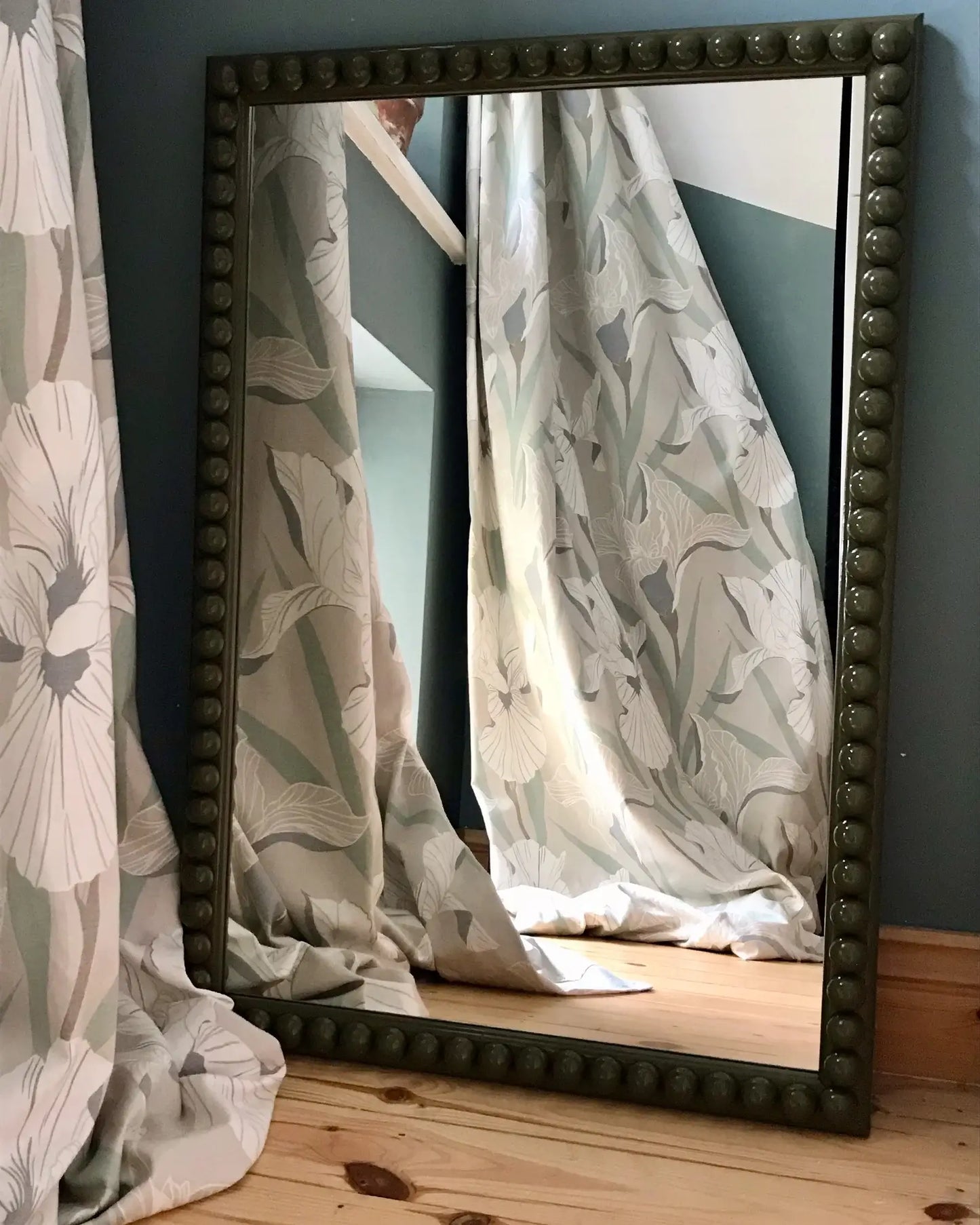 Olive Over-Sized Bobbin Mirror leaning against a wall